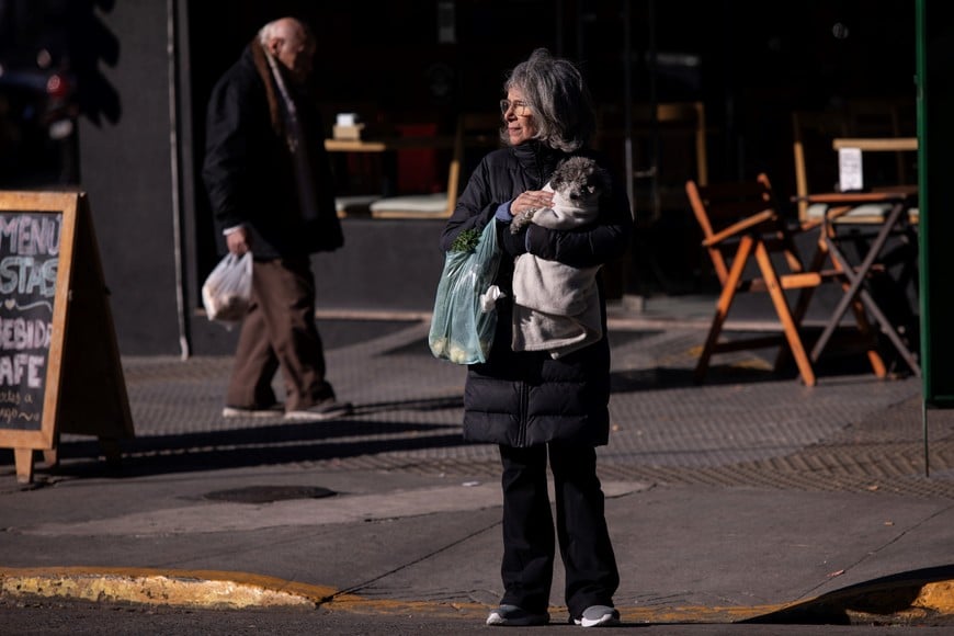 (240525) -- BUENOS AIRES, 25 mayo, 2024 (Xinhua) -- Una mujer porta ropa abrigadora mientras sostiene a su perro en brazos en una calle durante una ola de frío, en la ciudad de Buenos Aires, Argentina, el 25 de mayo de 2024. (Xinhua/Martín Zabala) (mz) (jg) (rtg) (da)