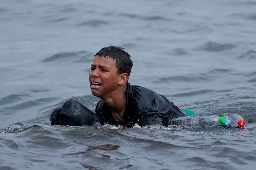 A Moroccan boy cries as he swims using bottles as floaters, near the fence between the Spanish-Moroccan border, after thousands of migrants swam across the border, in Ceuta, Spain, May 19, 2021. The boy attracted international media attention as he floated in a dark T-shirt with the bottles under his clothes and attached to his arms, crying as he reached the beach only to be led away by soldiers. "He didn't want to go back, he didn't have any family in Morocco, he didn't care if he died from cold; He preferred to die ... than go back to Morocco," soldier Rachid Mohamed al Messaoui said. "I never heard that from someone so young." REUTERS/Jon Nazca/File Photo     TPX IMAGES OF THE DAY SEARCH "GLOBAL POY" FOR THIS STORY. SEARCH "REUTERS POY" FOR ALL BEST OF 2021 PACKAGES.