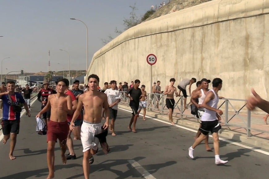 Migrants run and cheer as they cross on foot into the North African enclave of Ceuta from Morocco, after swimming over from the Moroccan side and overwhelming police at the city's breakwater, according to Spain's Guardia Civil, in Ceuta, Spain, July 30, 2026, in this screengrab obtained from a handout video. FARO TV via REUTERS
SPAIN OUT. NO COMMERCIAL OR EDITORIAL SALES IN SPAIN. THIS IMAGE HAS BEEN SUPPLIED BY A THIRD PARTY.
