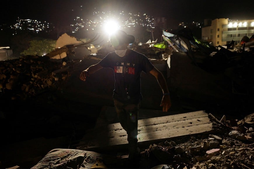Jose Luis Pacheco walks across the rubble as he searches for six of his family members still buried after the June 24 earthquakes that rocked Venezuela, killing and displacing thousands of people, in Caraballeda, La Guaira, Venezuela, July 29, 2026. REUTERS/Gaby Oraa