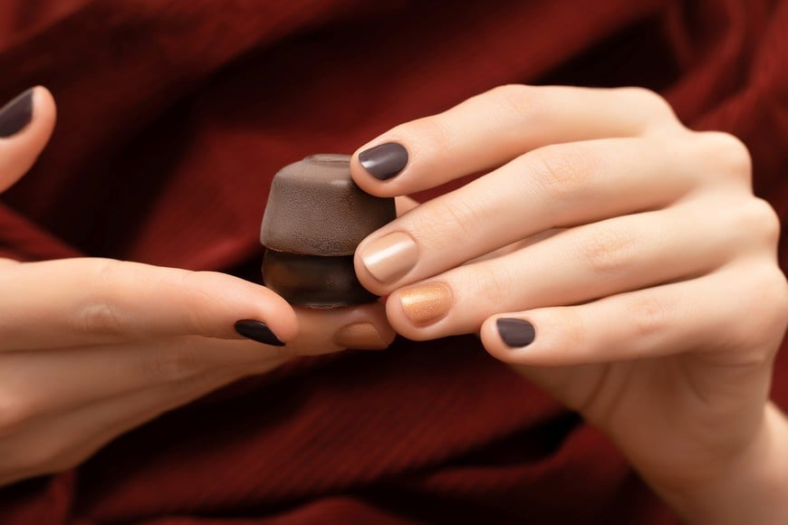 Brown nail design. Female hands holding chocolate candies
