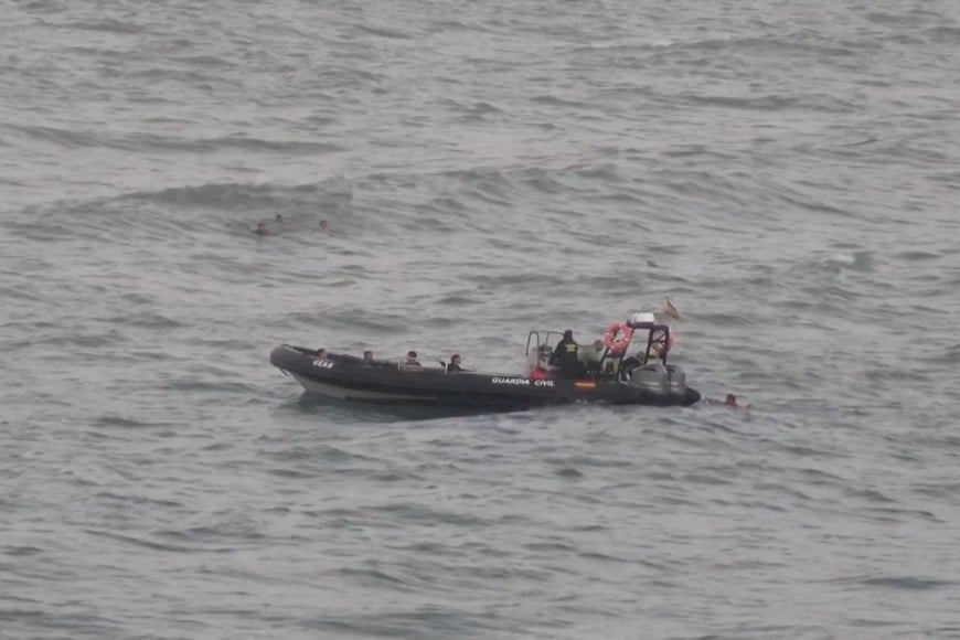 FILE PHOTO: A view shows migrants reaching a police boat, while other group of migrants swim in the background, as at least 54 children and about 30 adults swam from Morocco to Spain's North African enclave of Ceuta, in Ceuta, Spain July 25, 2025, in this screengrab obtained from a video. FARO TV/Handout via REUTERS    THIS IMAGE HAS BEEN SUPPLIED BY A THIRD PARTY. SPAIN OUT. NO COMMERCIAL OR EDITORIAL SALES IN SPAIN/File Photo