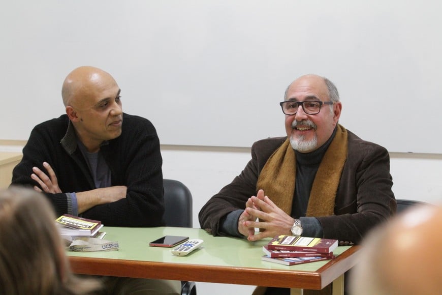 José Luis Serralunga (a la derecha de la imagen, vistos de frente) en 2019, junto a Fabián Pínnola, durante la presentación de distintos textos de su autoría en la Universidad Católica de Santa Fe.