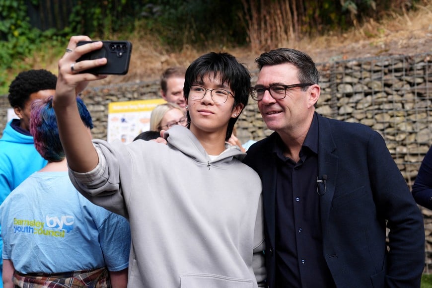 Britain's Prime Minister Andy Burnham has a selfie taken during a visit to a family centre in Sheffield, South Yorkshire, for the launch of the biggest transfer of power from Westminster in a generation, which will allow English mayors to keep a share of the taxes collected in their area, giving communities greater control over the decisions that shape jobs, transport, housing and public services. July 31, 2026. Annabel Lee-Ellis/Pool via REUTERS