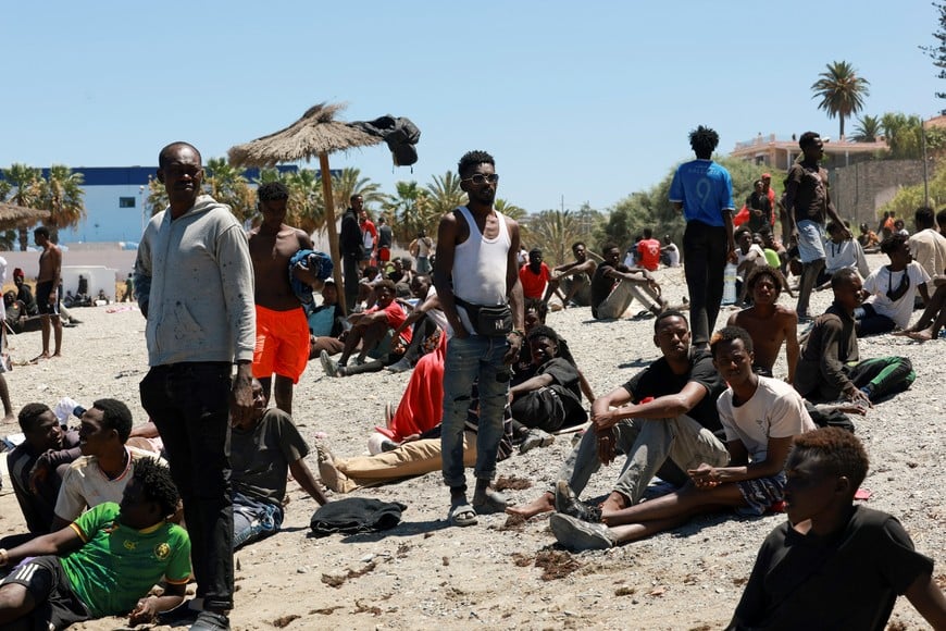 Migrants wait on the beach guarded by police, in Ceuta, Spain, following deadly mass crossings of migrants on foot and by sea from Morocco into Spanish territory, August 2, 2026. REUTERS/Violeta Santos Moura