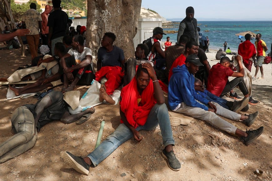Migrants await under the shade of a tree on a beach in Ceuta, following mass crossings of migrants on foot and by sea from Morocco into Spanish territory, in Ceuta, Spain, August 3, 2026. REUTERS/Violeta Santos Moura