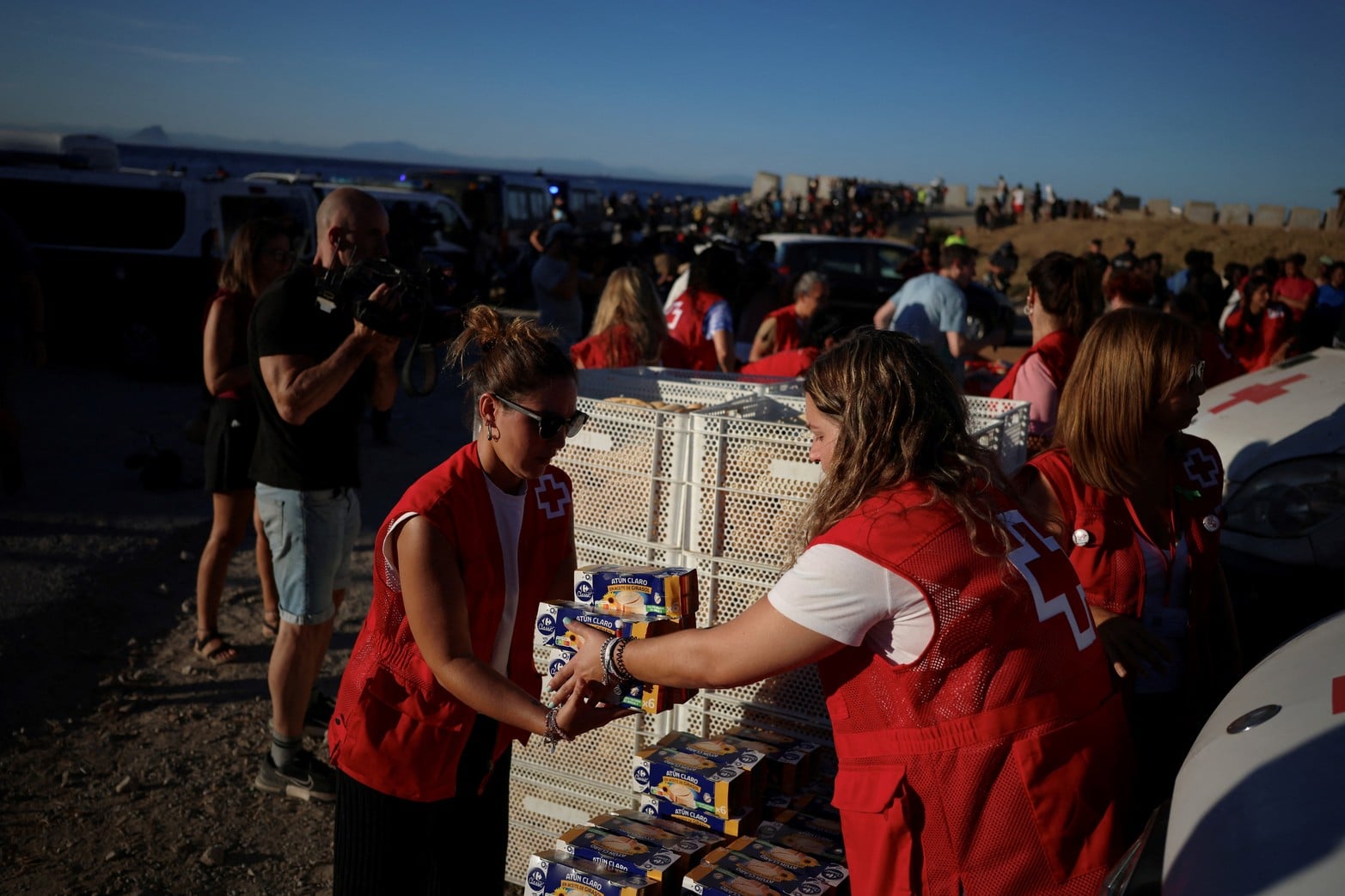Miembros de la Cruz Roja preparan alimentos y bebidas para distribuir a los migrantes, tras las travesías masivas a pie y por mar desde Marruecos.