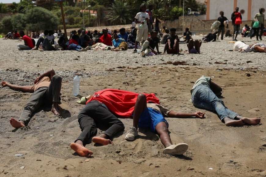 Migrants sleep while waiting on a beach following mass crossings of migrants on foot and by sea from Morocco into Spanish territory, in Ceuta, Spain, August 3, 2026. REUTERS/Violeta Santos Moura