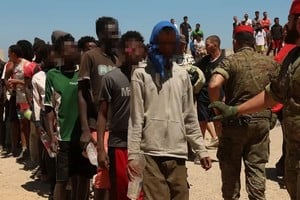 Los migrantes guardan fila este domingo para recibir agua del Ejército en Ceuta tras cruzar ilegalmente.