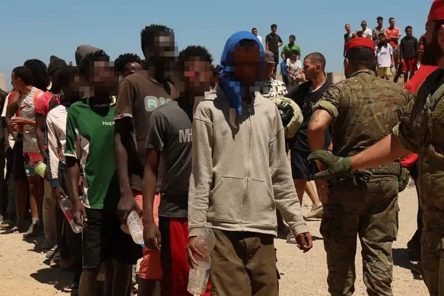 Los migrantes guardan fila este domingo para recibir agua del Ejército en Ceuta tras cruzar ilegalmente.