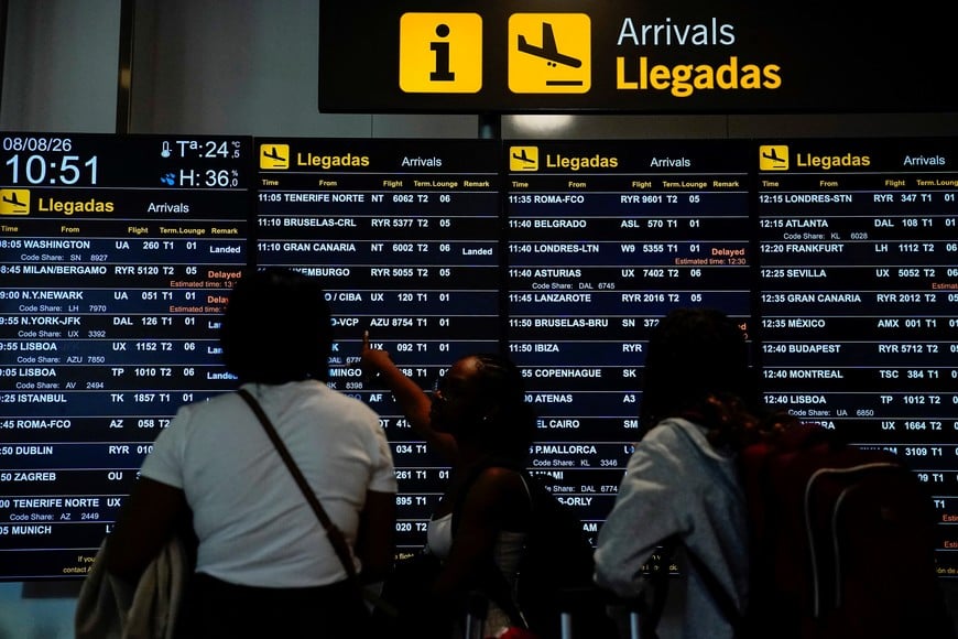 People look at an information panel displaying flight details at Adolfo Suarez Madrid–Barajas Airport, as Spain's government said it would establish border controls for flights and ships from Italy, from midnight on Saturday until September 7, in a dispute over irregular migration, in Madrid, Spain August 8, 2026. REUTERS/Ana Beltran