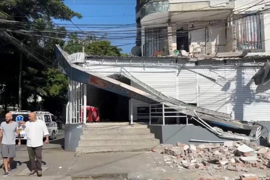 People walk past a damaged building in the aftermath of an earthquake in Cali, Colombia, August 10, 2026 in this screengrab taken from a video. REUTERS/Reuters TV