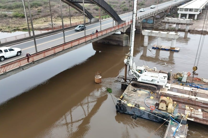 El viejo puente con su característico arco y, próximamente, el nuevo a la par. Gobierno provincial.