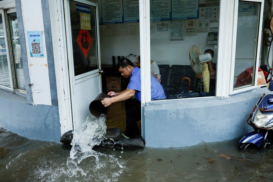 A person uses a bucket to remove water from a flooded room after Typhoon Dolphin brought heavy rain to Shanghai, China, August 10, 2026. REUTERS/Go Nakamura