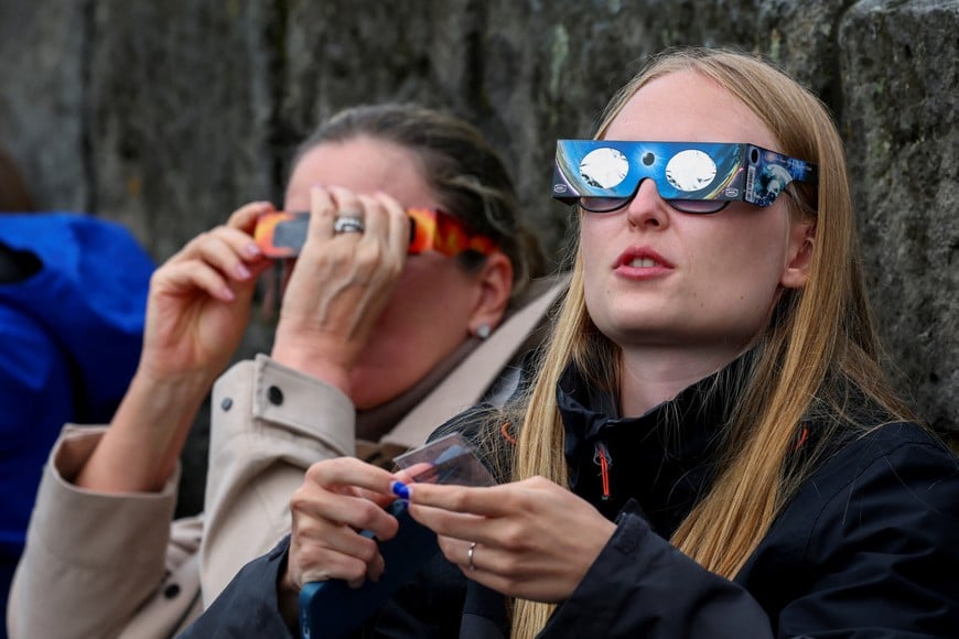 People use protective glasses to observe a solar eclipse, before totality, in Reykjavik, Iceland, August 12, 2026. REUTERS/Denis Balibouse