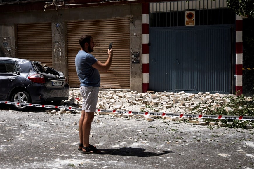 A passerby takes photographs of debris lying on the ground in the aftermath of an earthquake that struck southern Spain, in Granada, Spain, August 18, 2026. REUTERS/Fermin Rodriguez
