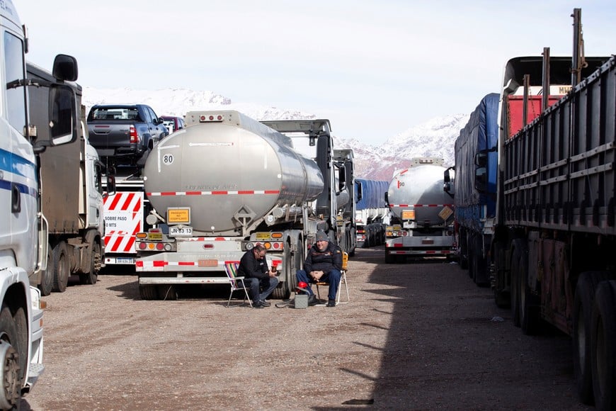 Truckers sit near parked vehicles while waiting for the Cristo Redentor border crossing between Argentina and Chile to reopen after heavy snowfall forced its closure, in Uspallata, Mendoza province, Argentina, July 22, 2026. REUTERS/Maximiliano Rios
