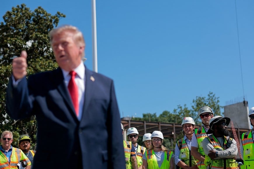 Construction workers stand while U.S. President Donald Trump speaks to reporters about the helipad that is being constructed on the South Lawn, at the White House in Washington, D.C., U.S., August 19, 2026. REUTERS/Kylie Cooper
