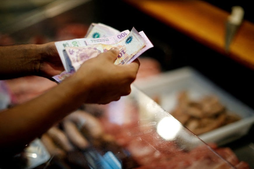 FILE PHOTO: A customer pays for pork meat in a local market in Buenos Aires, Argentina March 14, 2023. REUTERS/Agustin Marcarian/File Photo/File Photo