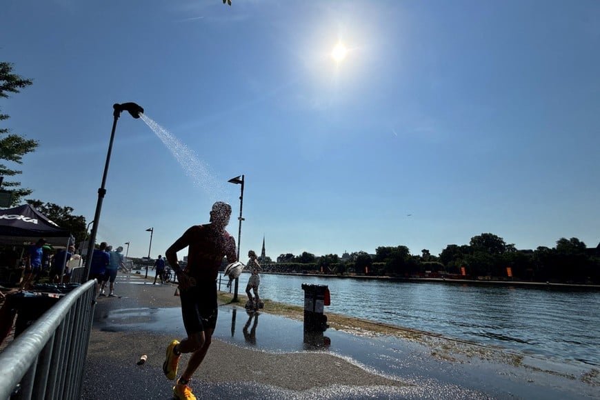 FILE PHOTO: An Ironman athlete runs past a shower near the Main River to cool off during the ongoing heat wave in Frankfurt, Germany, June 28, 2026.   REUTERS/Timm Reichert/File Photo