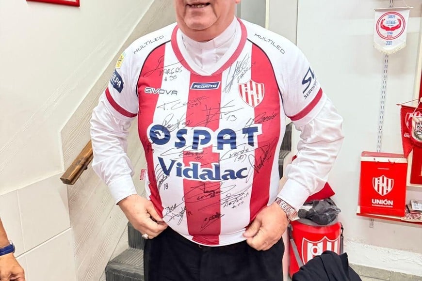 El obispo de Mar del Plata con la camiseta firmada por los jugadores en 2025, que él cedió a la flilal Emanuel Brítez