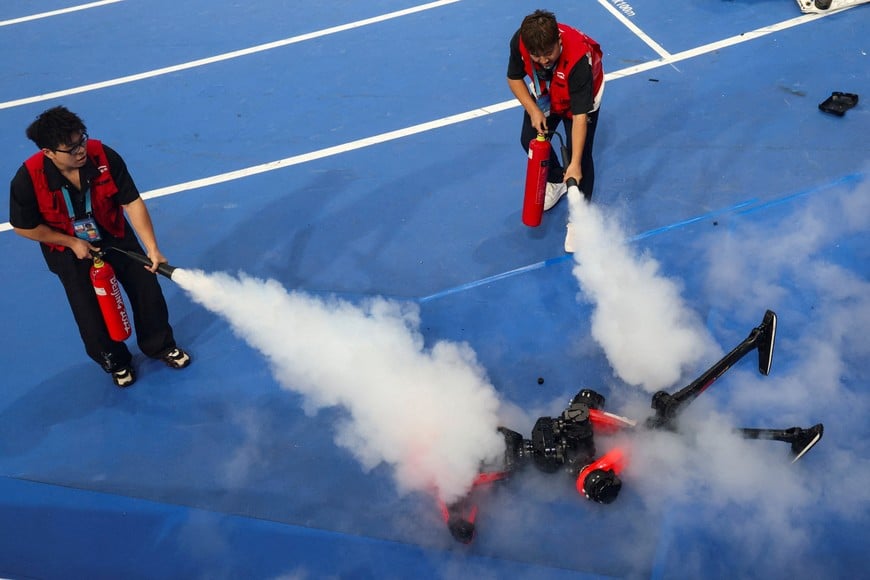 Maintenance team members use fire extinguishers on an Honor's Lightning humanoid robot following the 100m large-size group final race, at the 2026 World Humanoid Robot Games at the National Speed Skating Oval in Beijing, China, August 26, 2026. REUTERS/Tingshu Wang TPX IMAGES OF THE DAY