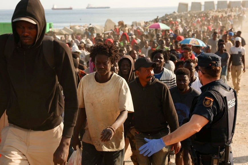 Migrants are escorted from a makeshift beach camp to official shelters across the city after authorities cleared the site, following a mass crossing from Morocco, in Spain's North African enclave of Ceuta, August 20, 2026. REUTERS/Violeta Santos Moura TPX IMAGES OF THE DAY