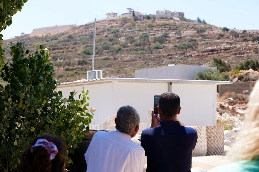 Qusra Mayor Abdulatheem Wadi points his mobile phone at Palestinian houses which were besieged by Israeli settlers in Qusra village in the Israeli-occupied West Bank August 13, 2026. REUTERS/Ali Sawafta