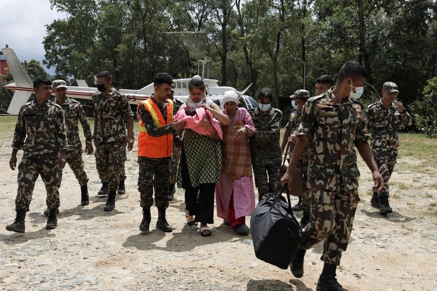 A family member carries an infant as the mother walks beside them after being rescued and airlifted from flood-affected areas at Maithali Barrack, an army training centre that serves as a primary base for airlifting survivors, following flash floods and a mudslide, in Trishuli, Nuwakot district, Nepal, August 29, 2026. REUTERS/Navesh Chitrakar