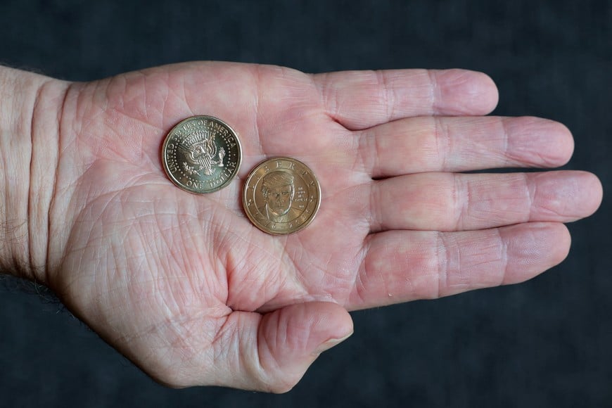 A person holds $1 coins with U.S. President Donald Trump's portrait, in honor of the nation's 250th anniversary of independence, on the day the coin is released for sale, is seen in this illustration taken, September 2, 2026. REUTERS/Kylie Cooper/Illustration