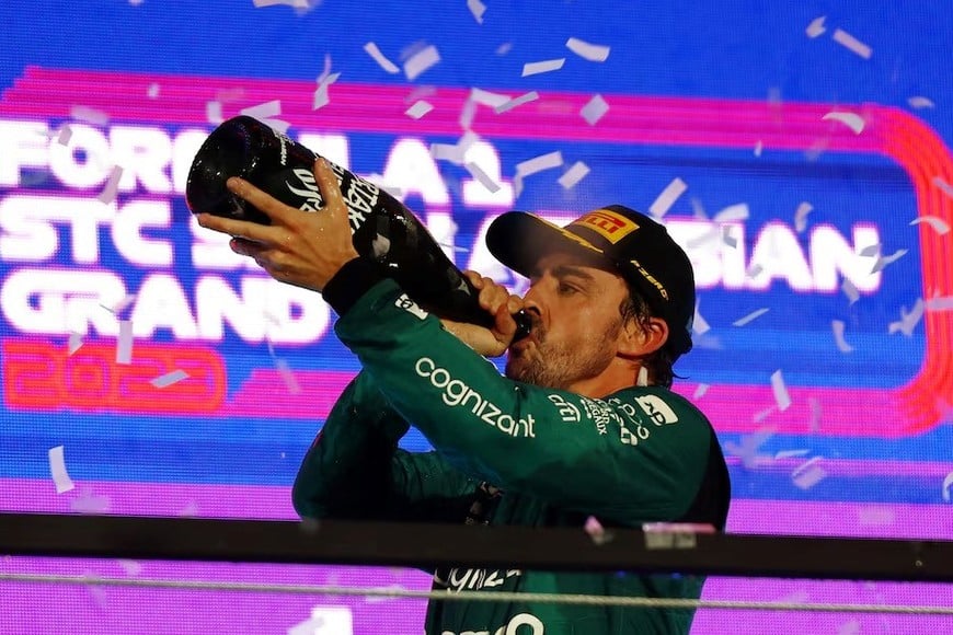 Fernando Alonso de Aston Martin bebe champán en el podio tras terminar tercero en el Gran Premio de Arabia Saudí antes de recibir una penalización de 10 segundos que le hace caer a la cuarta posición en los resultados finales.