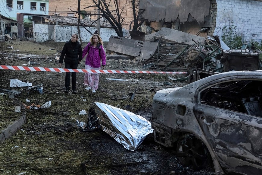 Residents stand near a body covered with a thermal blanket on the ground at a site of a Russian missile strike, amid Russia's attack on Ukraine, in Kyiv, Ukraine September 8, 2026. REUTERS/Stringer TPX IMAGES OF THE DAY