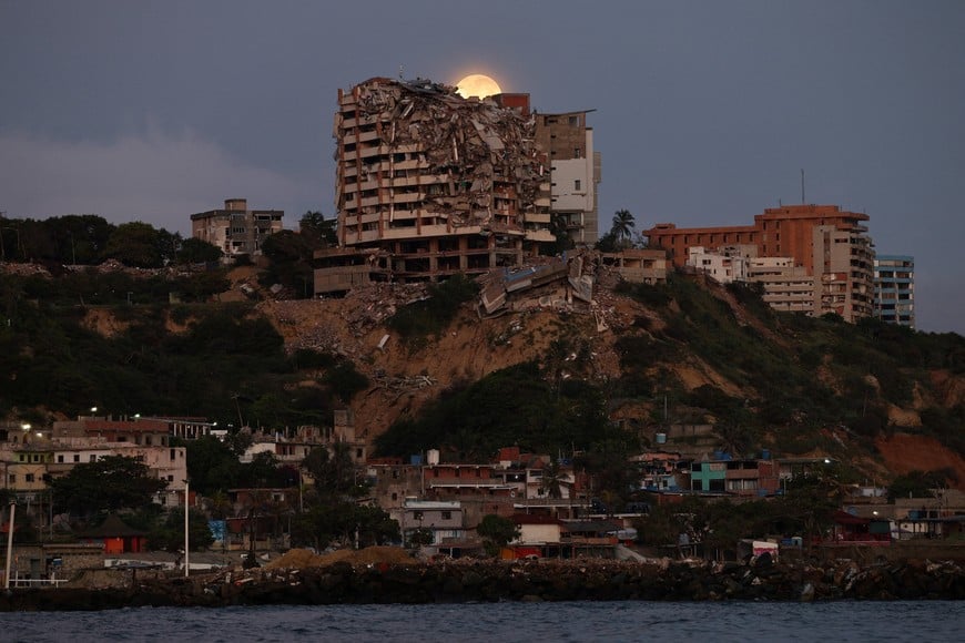 A full moon is seen behind a collapsed residential building damaged in the June 24 earthquakes, after a lunar eclipse, in La Guaira, Venezuela, August 28, 2026. REUTERS/Gaby Oraa
