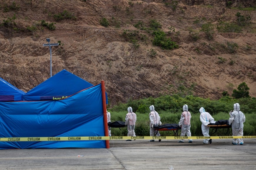 Members of the Philippine Coast Guard carry body bags containing the remains of victims of a fire aboard the MV June Aster ferry off the coast of Palawan to a tent in Coron, Philippines, September 12, 2026. REUTERS/Eloisa Lopez