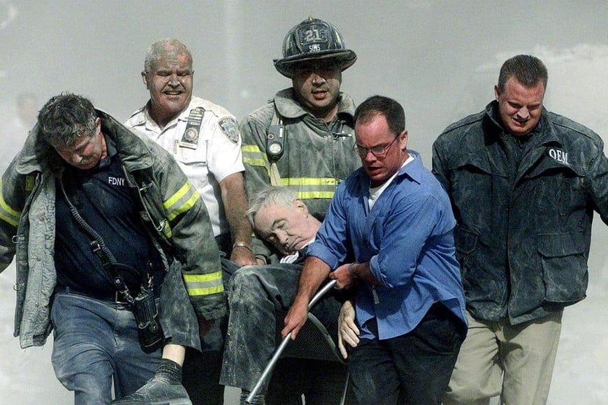 Bomberos y personal de rescate evacuan a uno de los heridos en las Torres Gemelas, el 11 de septiembre de 2001. El horror de lo ocurrido no solo sacudió la geopolítica mundial, sino que dejó en evidencia cómo el poder posmoderno opera a través de la estetización del conflicto y la administración simbólica de las masas a través del miedo inoculado.