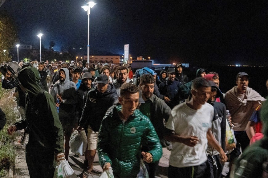 Police escort migrants from Benitez Beach to be relocated to the camp set up at the port of Ceuta, Spain, September 18, 2026. REUTERS/ Anna Surinyach