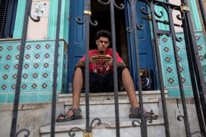 A man uses his mobile phone while sitting at the entrance of a building during a power outage in Havana, Cuba, September 18, 2026. REUTERS/Ricardo Arduengo