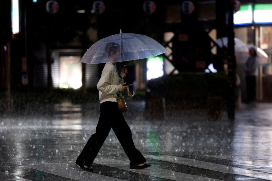 A woman crosses a street in heavy rain as a result of Typhoon Dujuan in Tokyo, Japan, September 21, 2026. REUTERS/Kim Kyung-Hoon