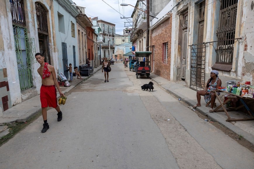 A young man carries plantains while walking past a street vendor selling goods on a residential street, as conditions deteriorate in Cuba amid a US-imposed oil blockade that has contributed to fuel shortages and prolonged power cuts, after US President Donald Trump said his administration was seeking a fundamental change in the situation in Cuba, in Havana, Cuba, September 22, 2026. REUTERS/Ricardo Arduengo