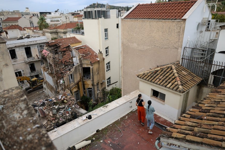 People inspect their building for damage from its rooftop after a neighbouring building partially collapsed following an explosion in the Plaka area, which is popular with tourists, in central Athens, Greece, September 26, 2026. REUTERS/Stelios Misinas