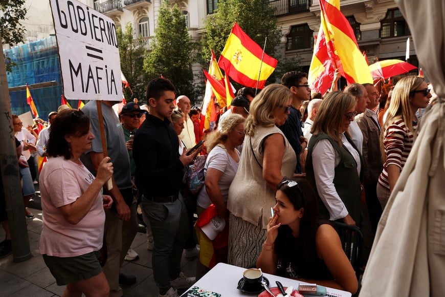 A woman sits at a table, as protesters march to call for general elections and to protest against the government's handling of Ceuta’s migrant crisis, in Madrid, Spain, September 26, 2026. REUTERS/Susana Vera