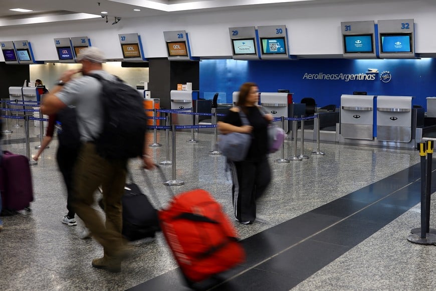 People walk near the Aerolineas Argentinas airline counter at the Aeroparque Jorge Newbery airport, in Buenos Aires, Argentina December 26, 2024. REUTERS/Agustin Marcarian