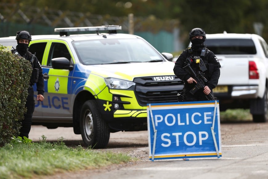 An armed police officer stands guards on a road outside the perimeter of the RAF Fairford airbase, after police declared a major incident at the base after several men were arrested on suspicion of offences under the Explosives Act, in Fairford, Gloucestershire, Britain, September 28, 2026. REUTERS/Toby Shepheard