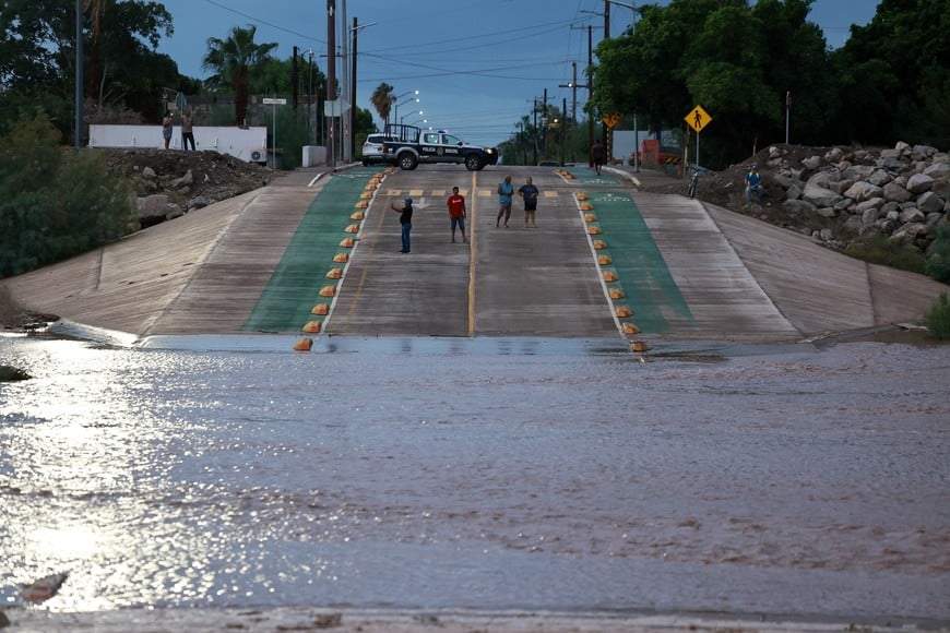 People stand on a flooded road after Hurricane Polo made landfall in Baja California Sur, in Loreto, Mexico, September 29, 2026. REUTERS/Raquel Cunha