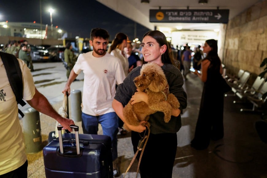 A woman carries a dog while, as passengers who were on the FlyDubai aircraft bound for Israel from the United Arab Emirates, which was diverted to Saudi Arabia following an emergency signal, arrive at the Ben Gurion International Airport, in Lod, near Tel Aviv, Israel, September 30, 2026. REUTERS/Ammar Awad