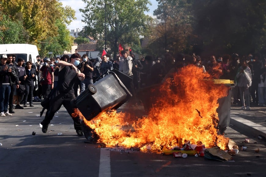 A masked protester throws a garbage bin into a fire set up by high school and university students in a street amid clashes with French riot police during a student protest to demand the hiring of substitute teachers, increased resources and better learning conditions, and to support the ongoing high-school student movement in the Seine-Saint-Denis department, in Saint-Denis near Paris, France, October 1, 2026. REUTERS/Abdul Saboor TPX IMAGES OF THE DAY