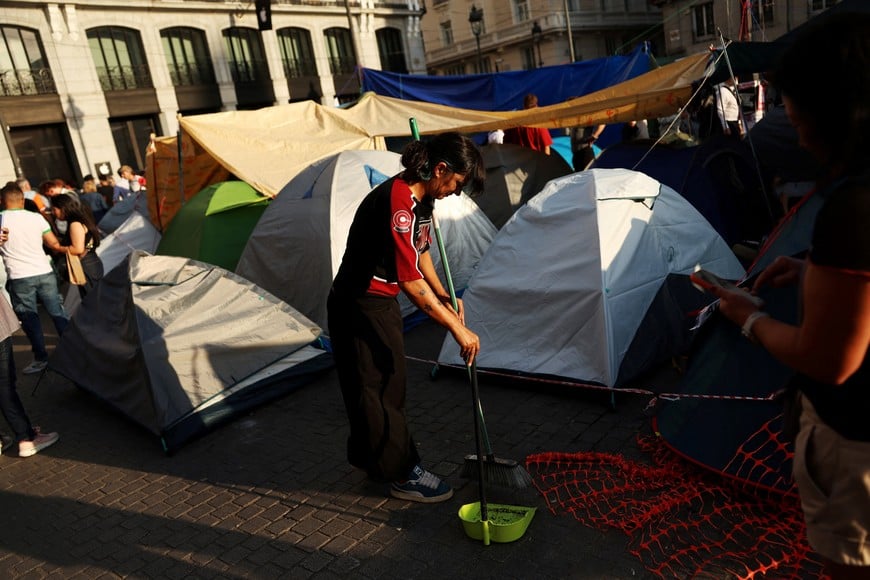 A demonstrator sweeps the floor at a camp at Madrid's downtown square, Puerta del Sol, set up to demand political action to stop evictions and alleviate the housing crisis, after the forceful eviction of an 87-year-old woman from her apartment in Madrid, Spain, October 5, 2026. REUTERS/Susana Vera