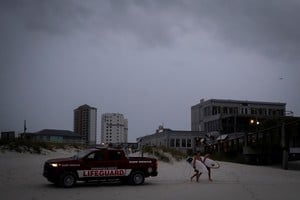 Surfers walk past a Pensacola Beach Lifeguard patrol as Hurricane Isaias moves through the Gulf of Mexico and is forecast to strengthen before reaching the US Gulf Coast, in Pensacola Beach, Florida, US, October 9, 2026. REUTERS/Marco Bello