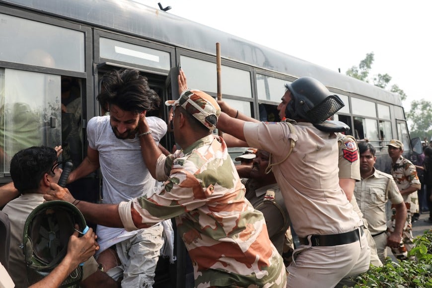 Security personnel try to stop a protester trying to get off the police bus after being detained, during a protest organised by the Cockroach Janta Party (CJP) seeking the resignation of India's Chief Election Commissioner, Gyanesh Kumar, in New Delhi, India, October 10, 2026. REUTERS/Priyanshu Singh