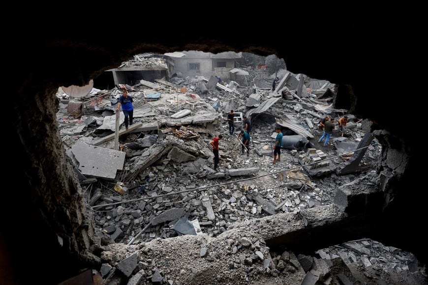Palestinians inspect the site of a house targeted by Israeli airstrikes after the Israeli military warned residents to evacuate late on Saturday, in Al-Zawayda, central Gaza Strip, October 11, 2026. REUTERS/Mahmoud Issa